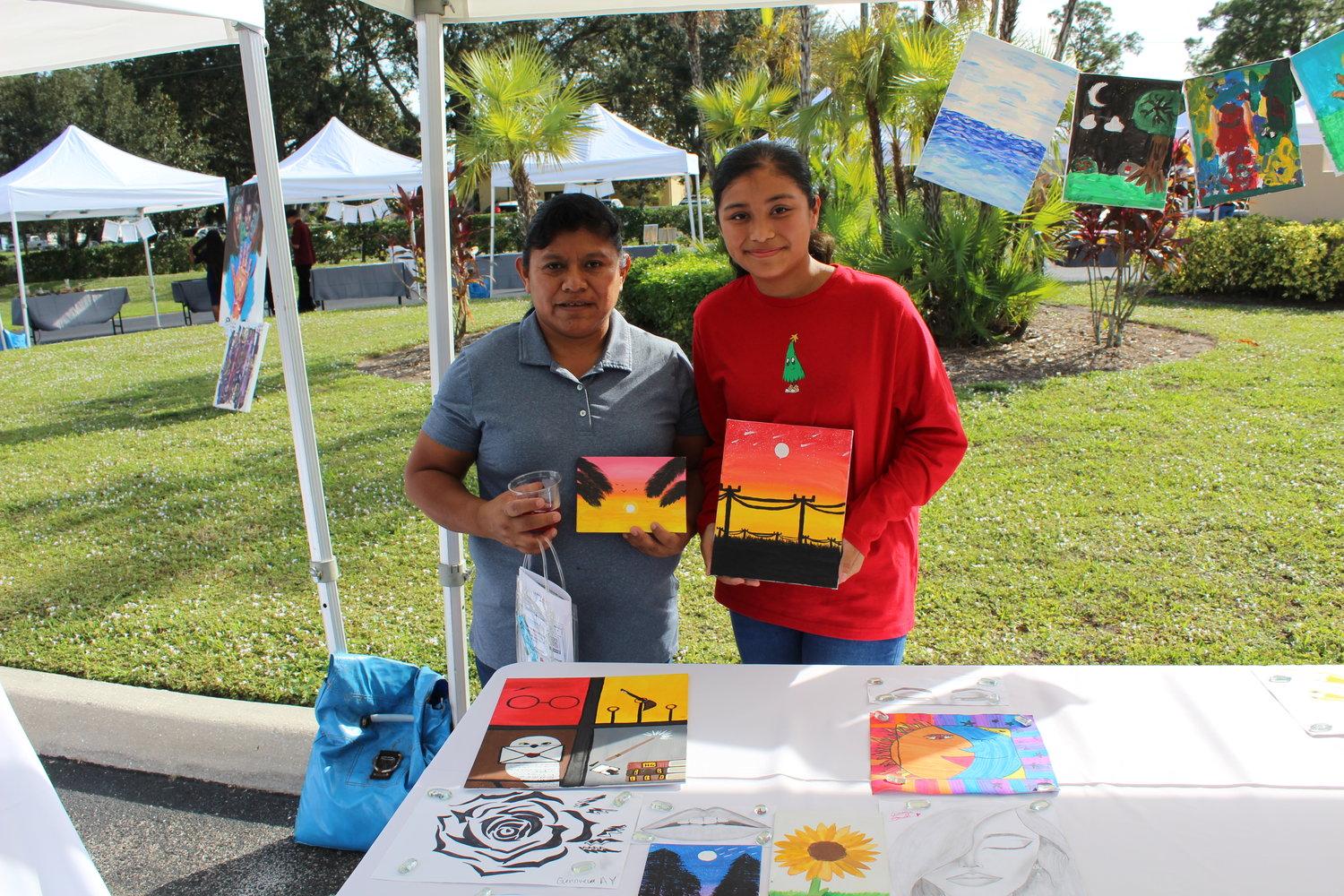 Assisted by her mother, Immokalee Foundation student Genoveva A. shows her artwork.